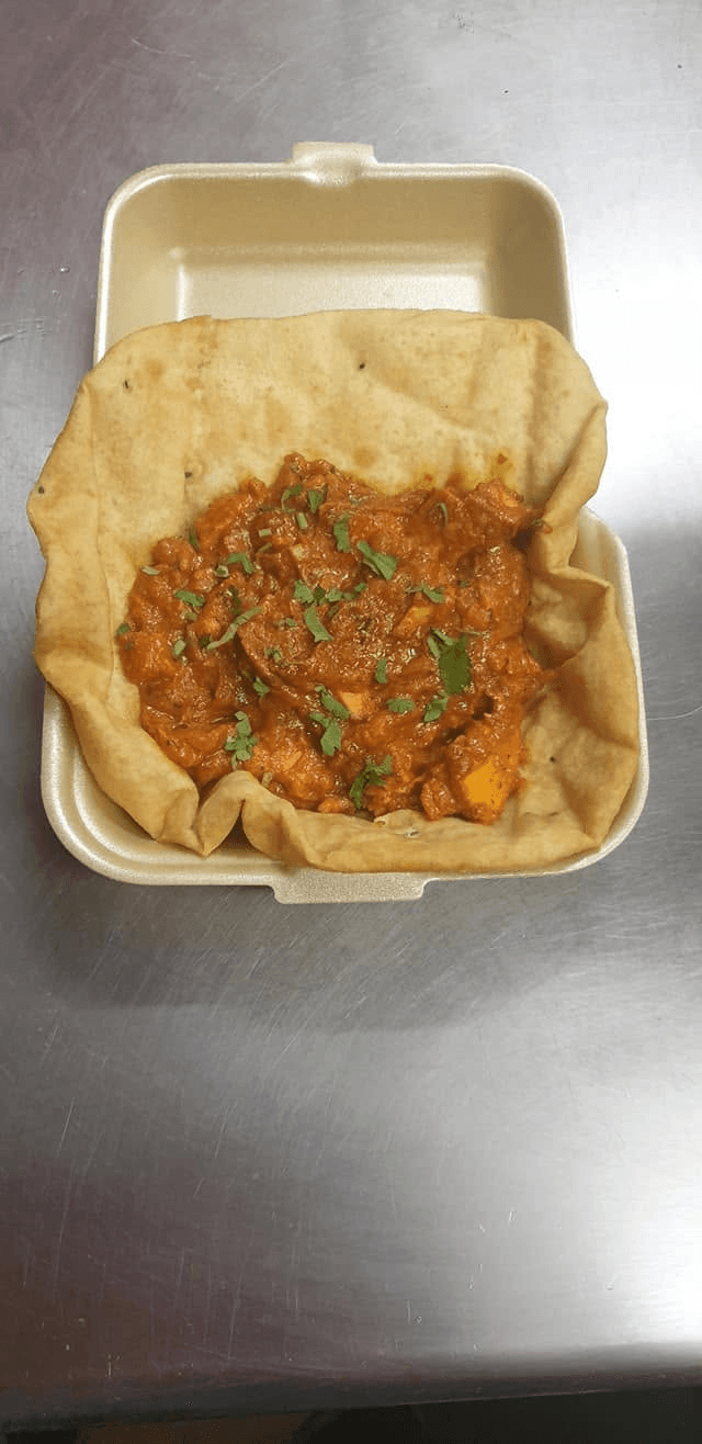 Freshly prepared curry served with bread in a takeaway box
