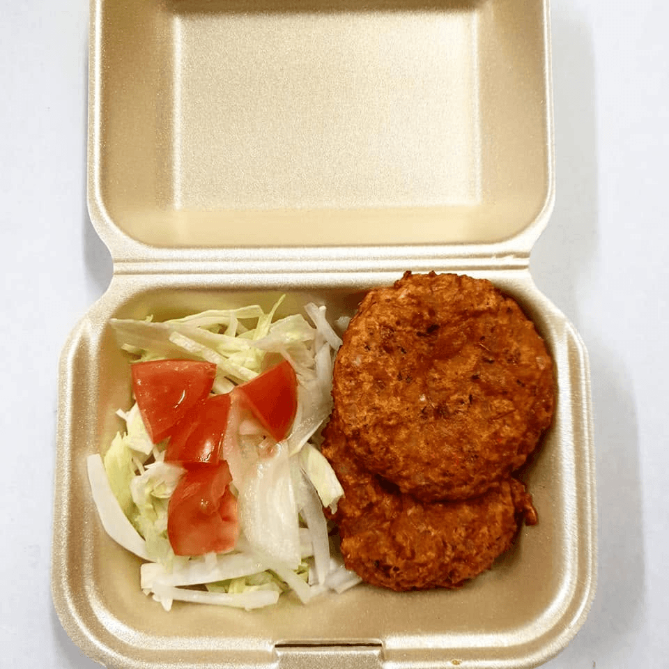 Freshly prepared savoury fritters with salad in a takeaway box