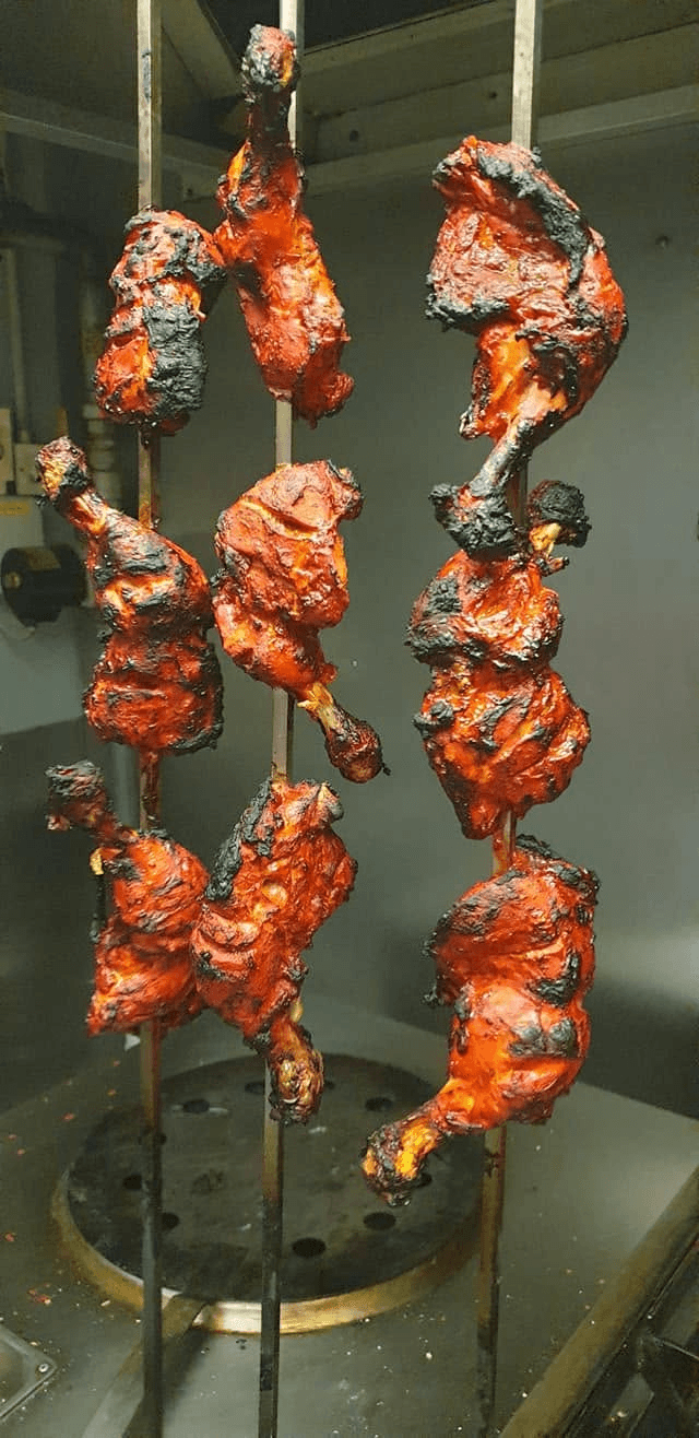 Tandoori chicken cooking on skewers in Saffron's kitchen